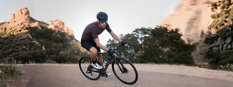 Mies polkee pyörällä asfaltilla, taustalla näkyy vuoristoja mitä näkee tyypillisimmin aavikoilla
