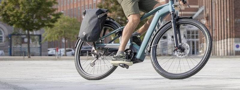 Pyörälaukut ovat kiinni pyörän tavaratelineessä jota kuljettaja ajaa kaupungissa